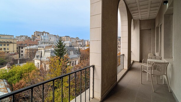 Ein Balkon mit Blick auf eine Stadtlandschaft, die moderne und historische Gebäude vereint.