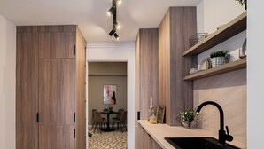 Eine moderne Küche mit Holzschnitzereien, einem schwarzen Spülbecken und einem Essbereich im Hintergrund.