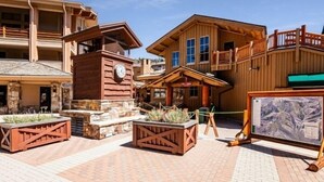 Un refugio rústico con fachada de madera, una torre del reloj y zonas de estar al aire libre.