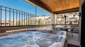 Un jacuzzi en un balcón con vistas a un paisaje montañoso.