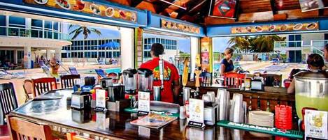 A restaurant with a wooden interior, a counter with various items, and a view of the beach outside.
