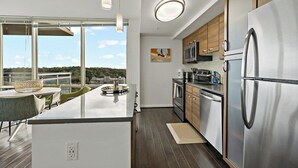 Cozinha moderna com uma ilha grande, eletrodomésticos de aço inoxidável e vista para o exterior.