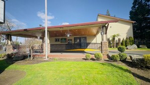 A hotel with a covered entrance, stone pillars, and a well-maintained lawn. - Evergreen Inn Portland Airport (Portland)