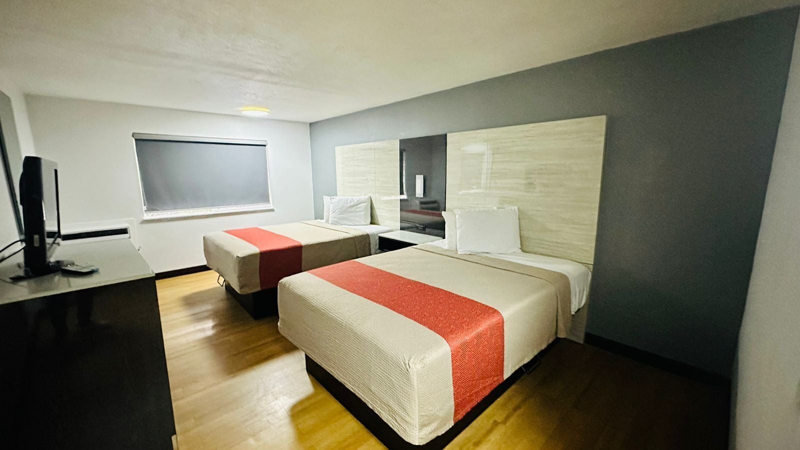 Ein Hotelzimmer mit zwei Betten, einem Schreibtisch und einem Fernseher.