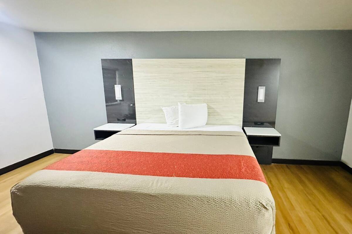 A hotel room with a bed, two bedside tables, and a nightstand.
