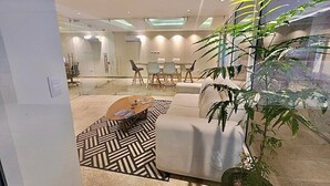 A modern living room with a sofa, coffee table, and a large plant.