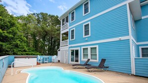 A blue building with a swimming pool, two lounge chairs, and a small deck area. - Oceanside,  Private Pool, Hot Tub, Community Amenities,  BH9, BeaContent (Corolla)