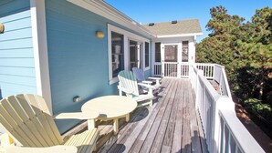 A wooden deck with Adirondack chairs and a table, overlooking a forested area. - Oceanside,  Private Pool, Hot Tub, Community Amenities,  BH9, BeaContent (Corolla)