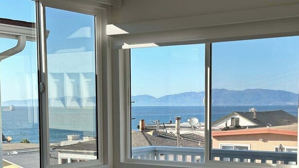 A living room with a large window offering a view of the sea and mountains.