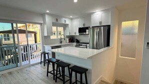 A modern kitchen with white cabinets, a stainless steel refrigerator, and a central island with bar stools.