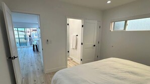 A bedroom with a large bed, a door leading to a bathroom, and a window.