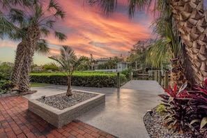 A landscaped garden with palm trees, a concrete planter, and a pathway.