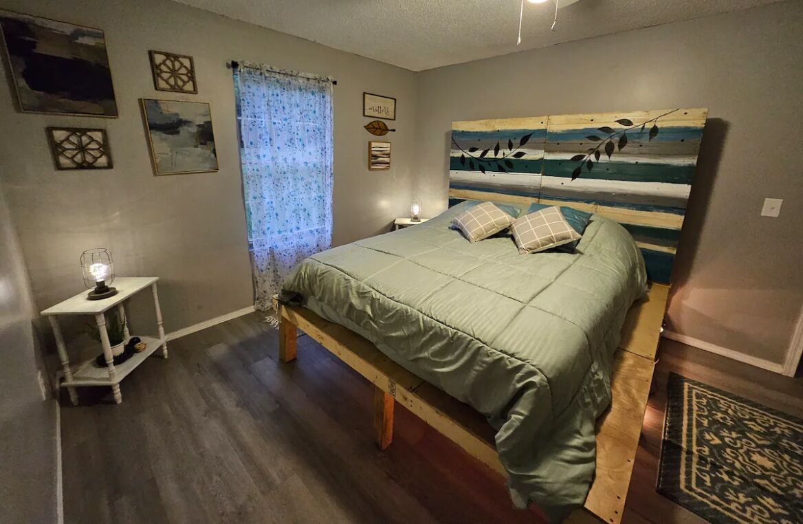 Ett sovrum med en säng, sängbord, en lampa och konstverk på väggarna.