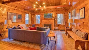 A cozy log cabin interior with a fireplace, wooden walls, and a comfortable seating area.