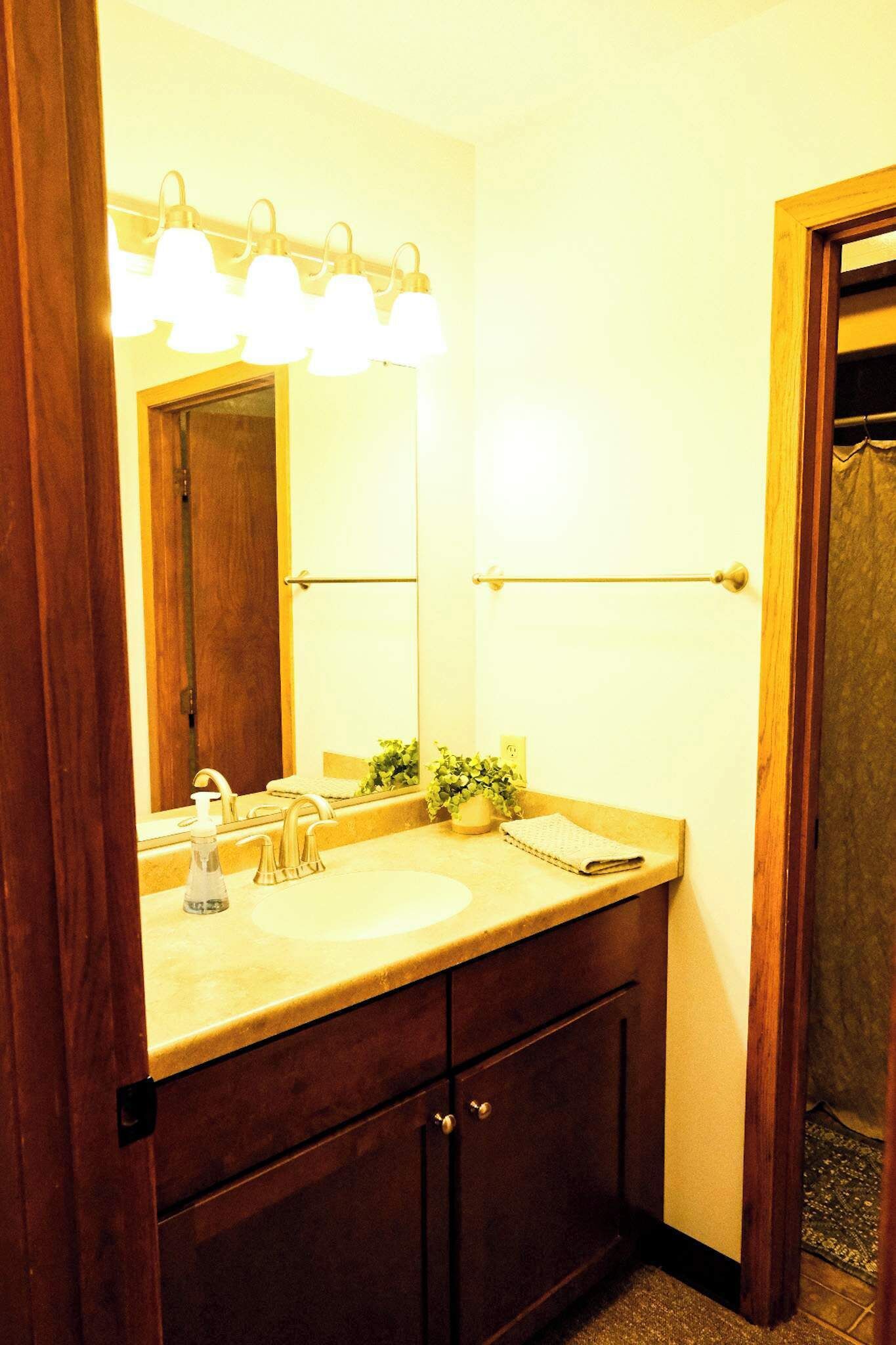 A bathroom with a double sink, a mirror, and a light fixture above the mirror.