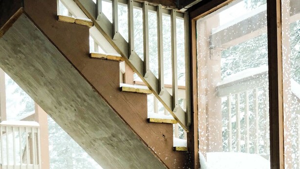 Two people in a hot tub with a wooden staircase and a view of a deck outside. - Slope Side Winter Villa I Alpen Villas at Powderhorn Mountain (Bessemer Township)