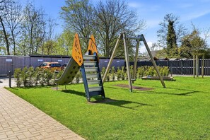 A playground with a slide, a ladder, and swings. - Glücksinsel Norddeich - 70sqm vacation apartment for up to 2 persons with garden and (Norddeich)