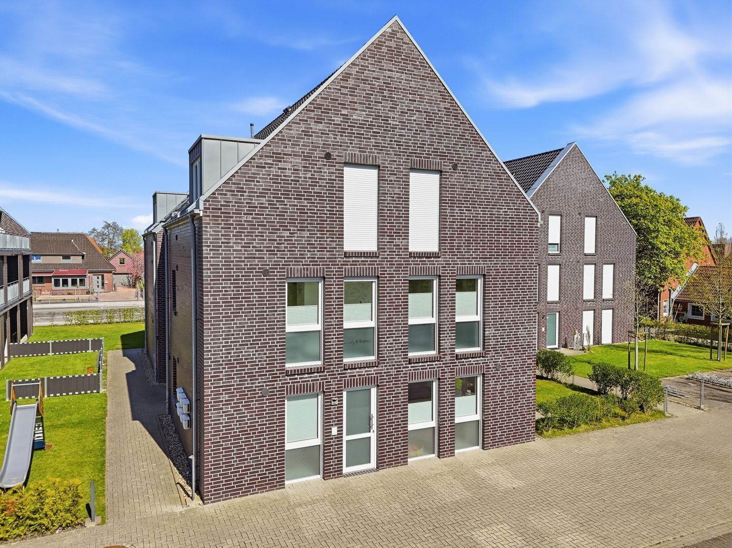 Een modern gebouw met een bakstenen gevel, grote ramen en een schuin dak.