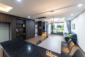 A modern interior with a dining area, a sofa, and a large window. - Hermen House in Jeju (Seogwipo)