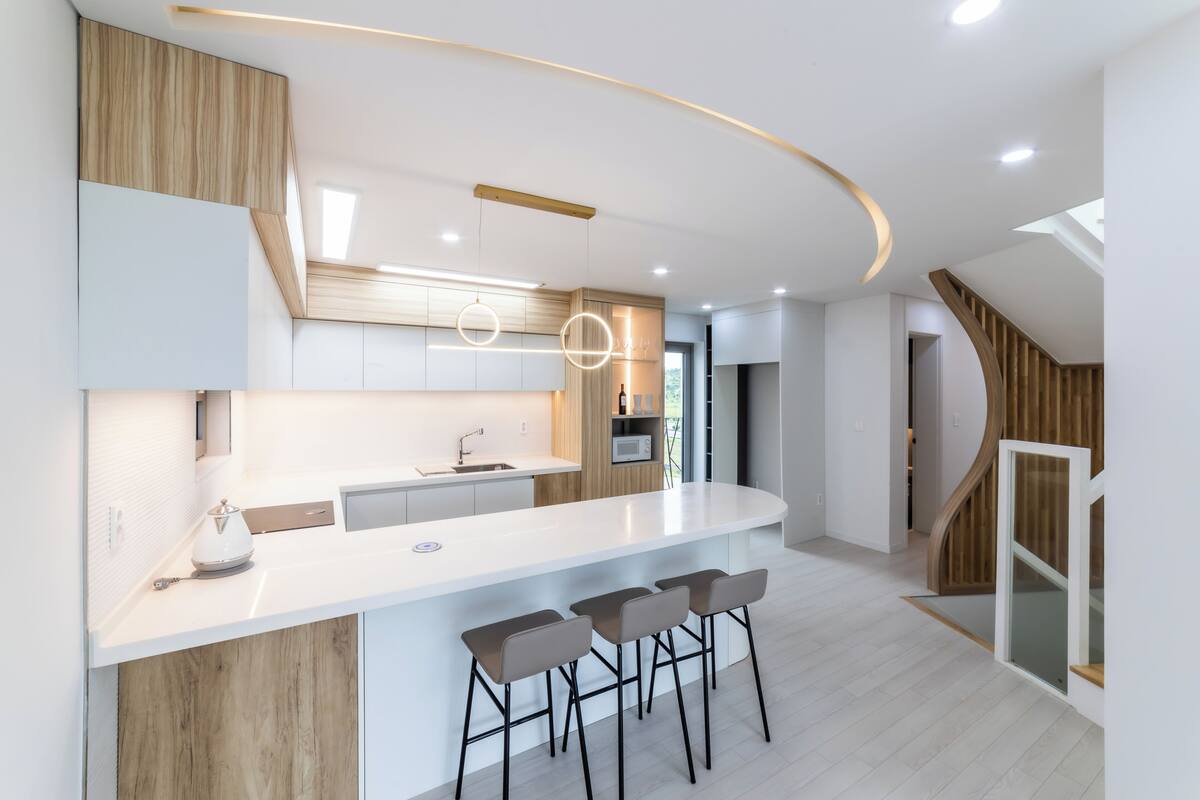 A modern kitchen with a central island, bar stools, and pendant lighting.