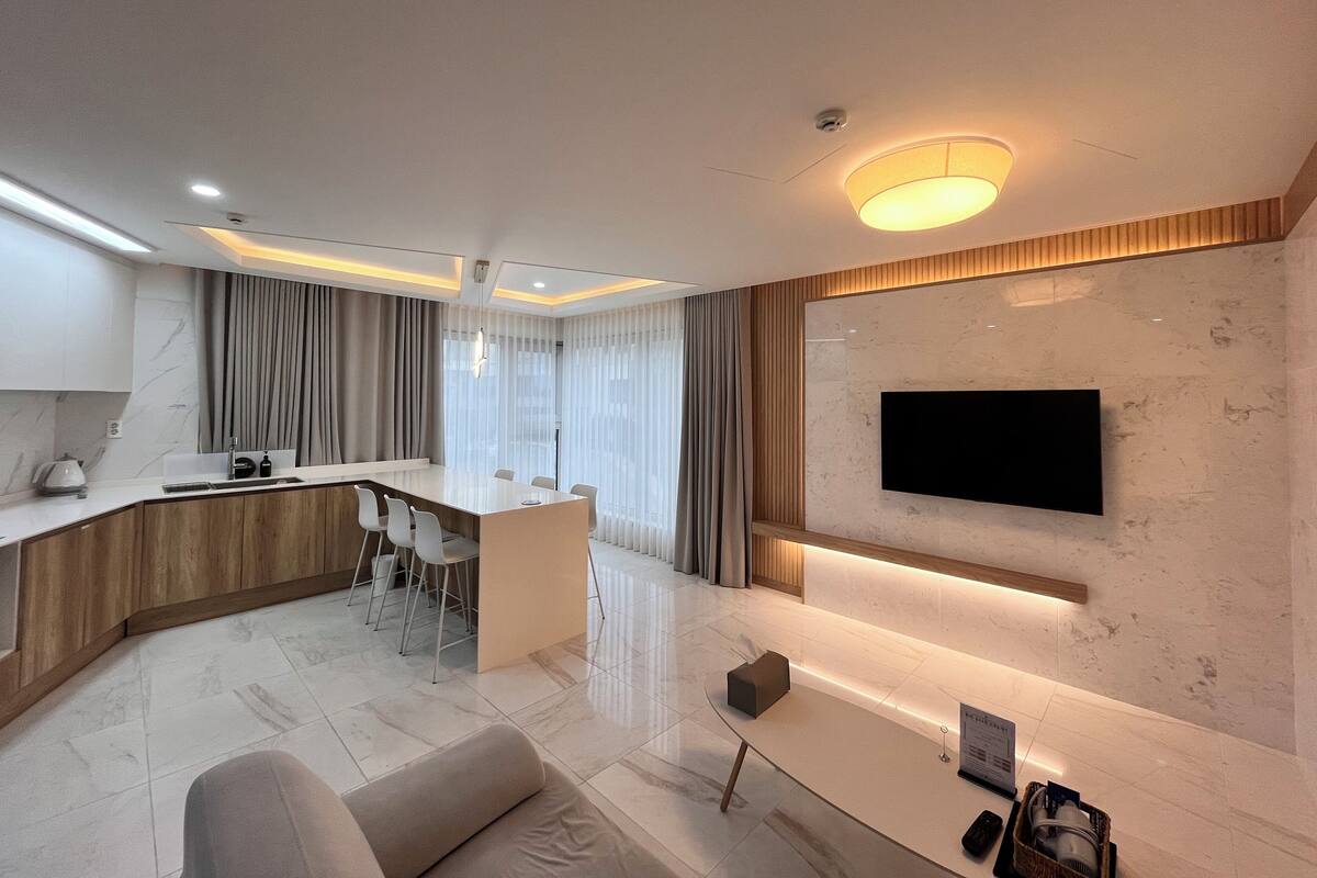 A modern living room with a sofa, a coffee table, and a TV mounted on the wall.