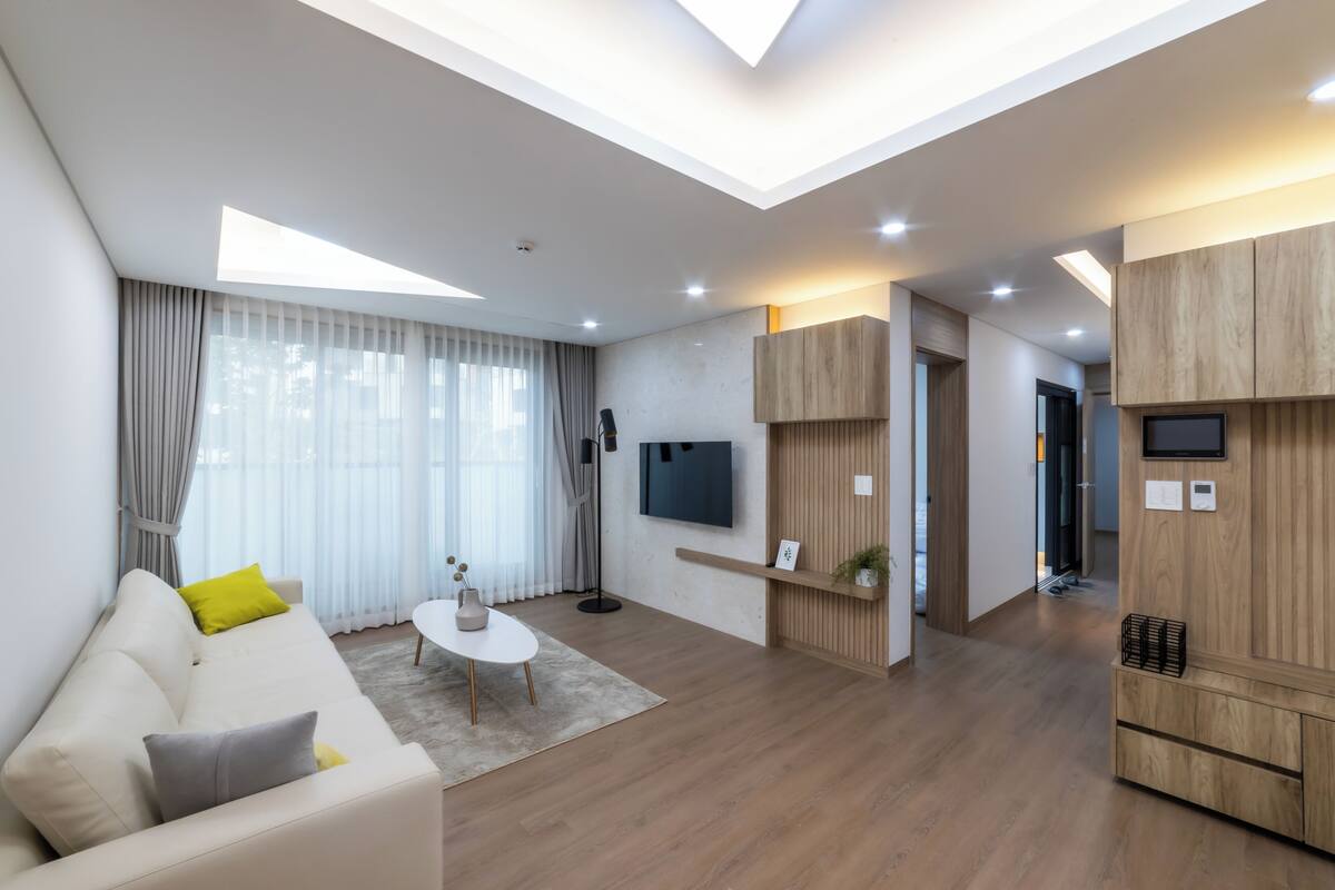 A modern living room with a sofa, coffee table, and a TV mounted on the wall.