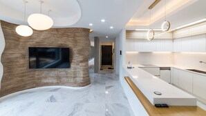 Eine moderne Küche mit einer geschwungenen Holzwand, einem integrierten Fernseher und einer eleganten Arbeitsplatte.