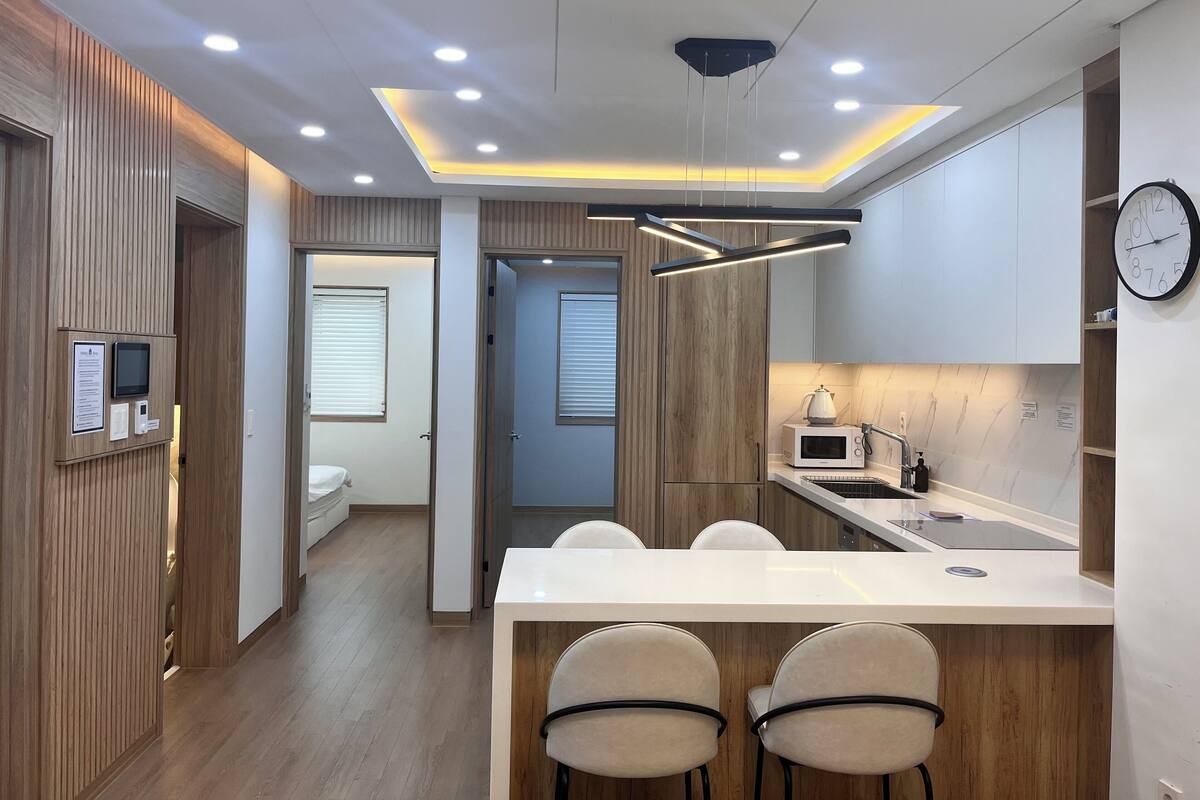 A modern kitchen with a central island, wooden paneling, and recessed lighting.