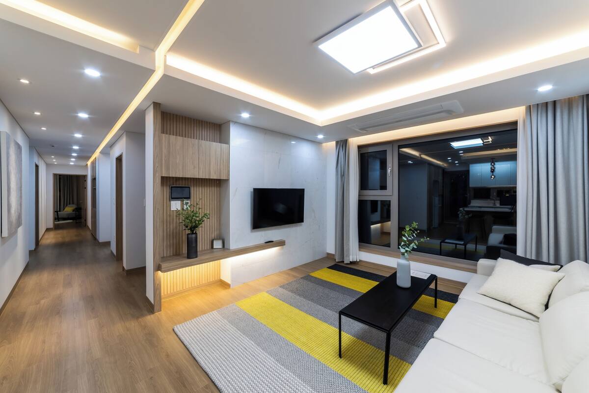 A modern living room with a sofa, a coffee table, and a flat-screen TV mounted on the wall.