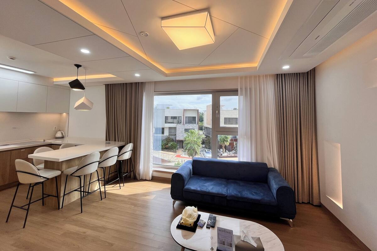 A modern living room with a sofa, a coffee table, and a dining area with chairs.