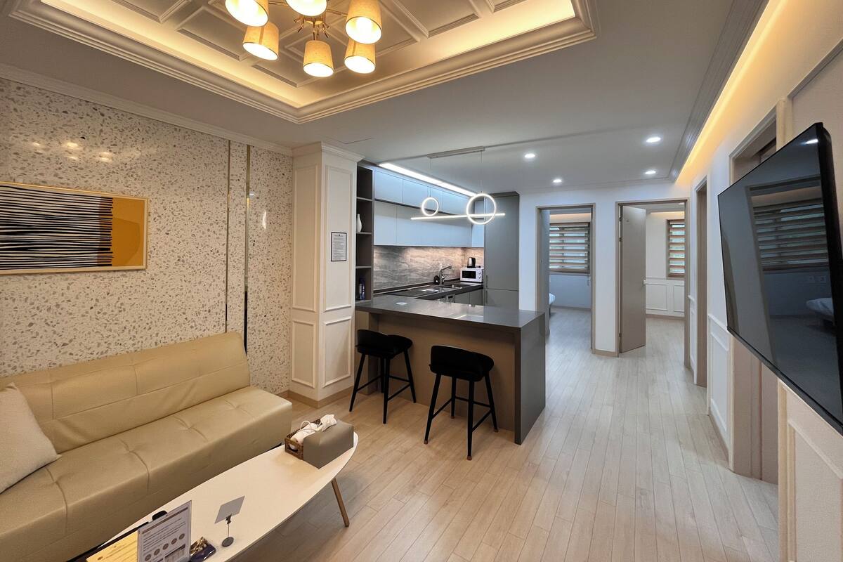 A modern living room with a sofa, a coffee table, and a kitchen area with a bar.