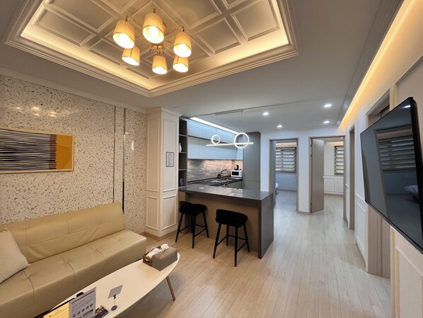 A modern living room with a sofa, a coffee table, and a kitchen area with a bar.