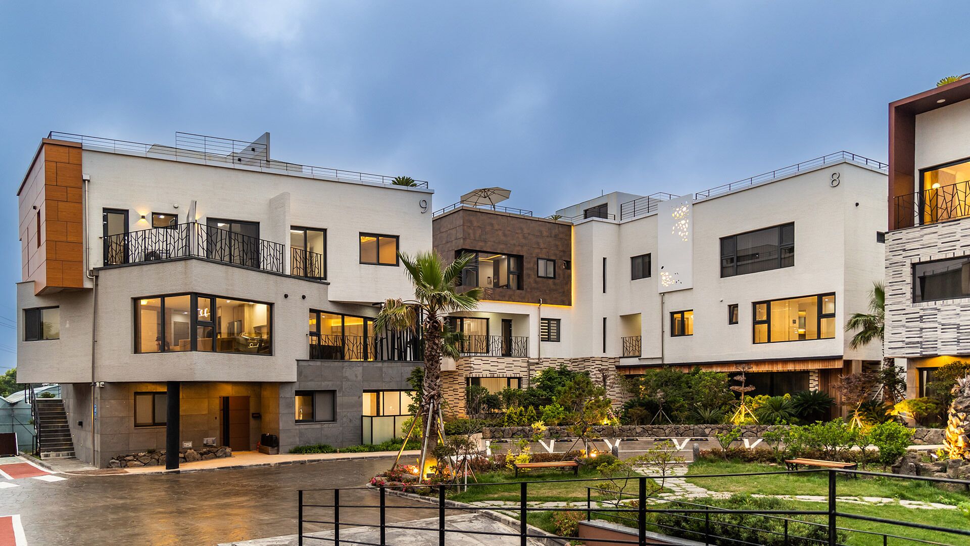 A modern multi-story residential building with balconies, large windows, and a landscaped courtyard.