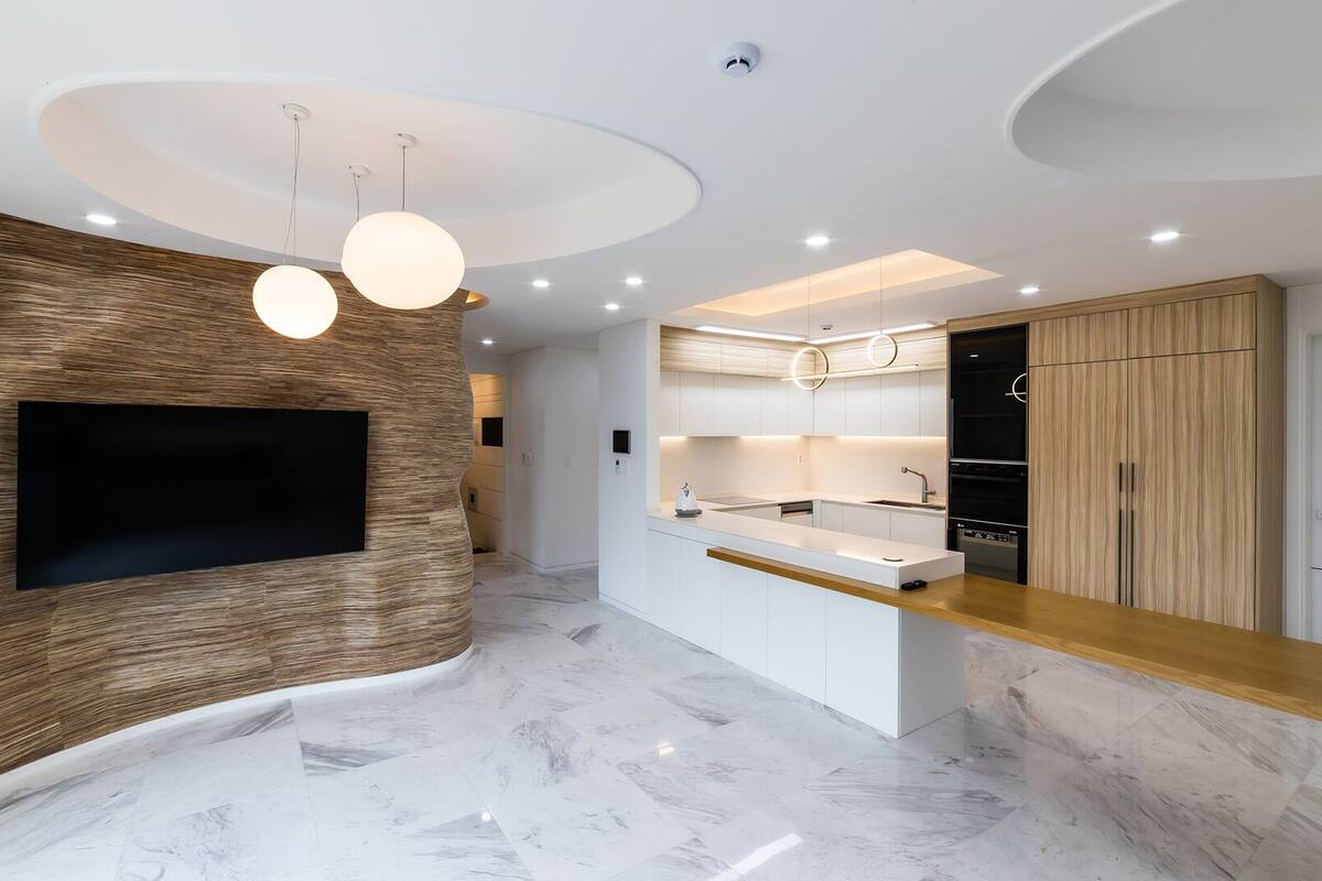 A modern kitchen with a built-in TV, wooden accents, and a marble floor.