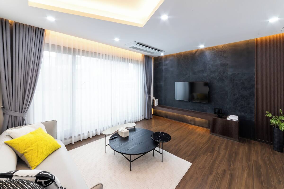 A modern living room with a sofa, coffee table, and TV mounted on a dark wall.