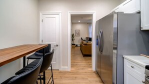 A modern kitchen with a wooden table and chairs, a stainless steel refrigerator, and a white cabinet. - Sleek Escape: Modern 3 BR- 4 Min from West Point ! (Highland Falls)
