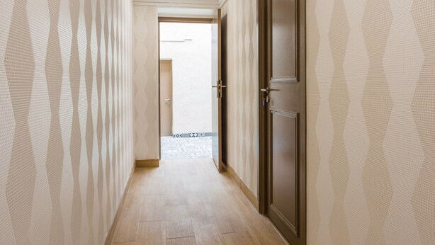 A hallway with patterned wallpaper, wooden flooring, and a door at the end. - Elegant Studio - 2P - Malakoff (Malakoff)