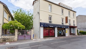 A building with a cafe and bar on the ground floor, featuring a stone facade and a tree in front. - Elegant Studio - 2P - Malakoff (Malakoff)
