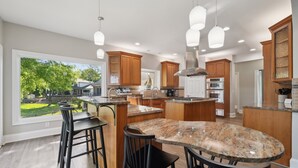 A spacious kitchen with a large island, wooden cabinets, and a view of a green landscape. - Lakeshore Lookout - Amazing Long Range Views, Pool, Hot Tub, Fire Pit, Theatre Room and much more! (Mooresville)
