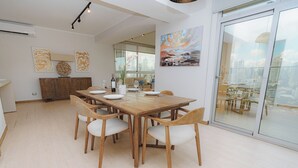 A modern dining area with a wooden table and chairs, a city view through large windows, and artwork on the walls. - Luxury 2BR Cityview apt, parking and balcony (Panamá)