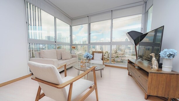 A modern living room with a sofa, armchairs, a coffee table, a TV, and a city view through large windows. - Luxury 2BR Cityview apt, parking and balcony (Panamá)