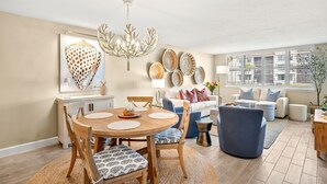 Un comedor con una mesa redonda de madera, sillas con cojines estampados y una lámpara de araña.