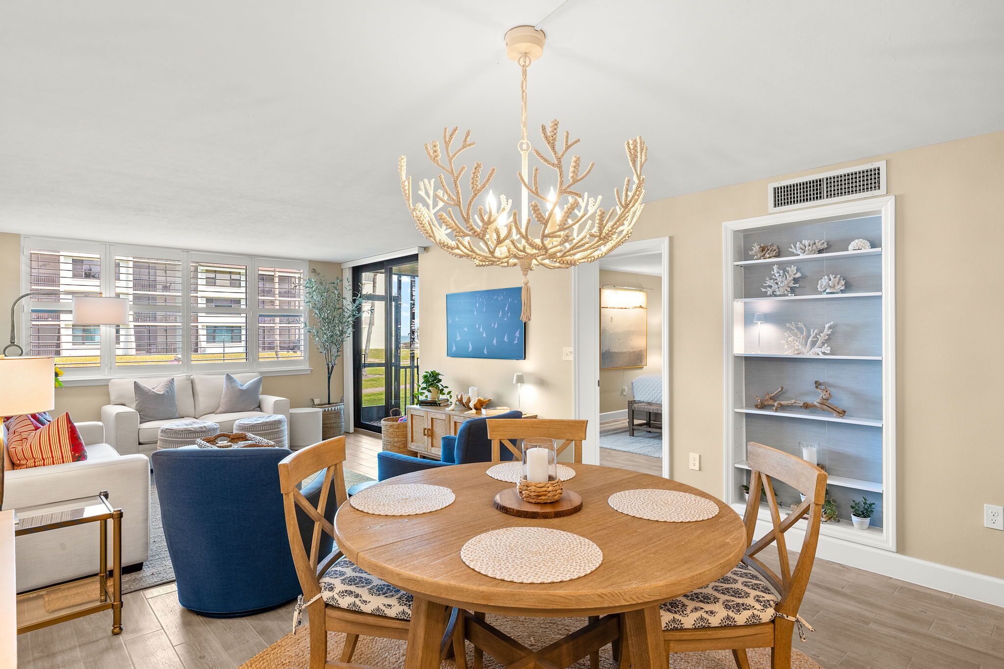 A dining area with a round wooden table, blue upholstered chairs, and a decorative chandelier.