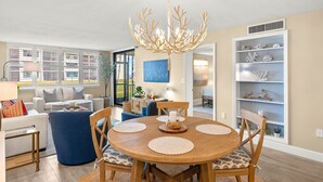 Un comedor con una mesa redonda de madera, sillas tapizadas en azul y una lámpara decorativa.