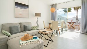 A modern living room with a sofa, a coffee table, and a dining area with chairs and a table. - Lanzahost Tabaiba Green (Costa Teguise)