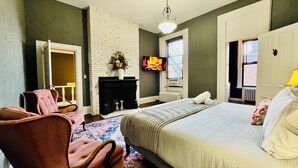 Una camera da letto con un letto, un camino, una televisione e una finestra con persiane.
