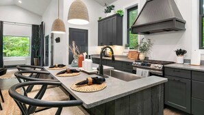Una cocina moderna con una isla central, muebles oscuros e iluminación colgante.