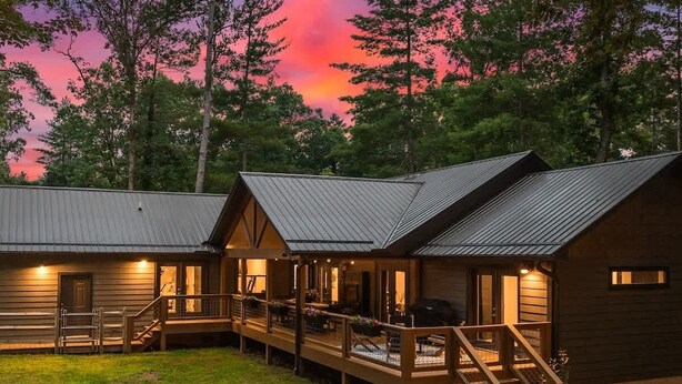 Una hilera de cabañas de madera con techos de metal, terrazas de madera y áreas de estar al aire libre.