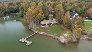 A lakeside property with a dock, a house, and a small boat. - Azalea Point by SoCharm | Quaint Lakefront Retreat (Sherrills Ford)