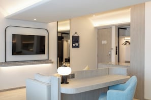 Un baño moderno con tocador, espejo y televisor en la pared.